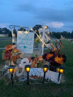 a sign that is sitting in the grass next to some lights and pumpkins on it