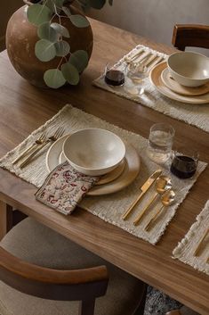 a wooden table topped with plates and silverware