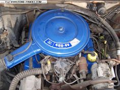 the engine compartment of a blue car with its hood up and it's hoses out