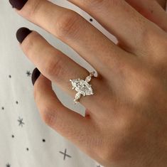 a woman's hand with a diamond ring on top of her finger and stars in the background