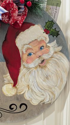 a santa clause painted on the side of a door with holly and red ribbon around it