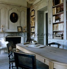 an old fashioned desk in the middle of a room with bookshelves and chairs