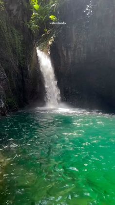 there is a waterfall in the middle of the water with green algae growing on it