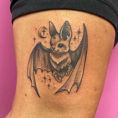 a bat tattoo on the side of a woman's thigh