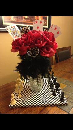 a vase filled with red roses sitting on top of a chess board covered in black and white pieces