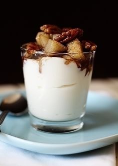 a glass filled with pudding and nuts on top of a blue plate