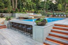 an outdoor pool with steps leading up to it and a bar in the middle surrounded by trees