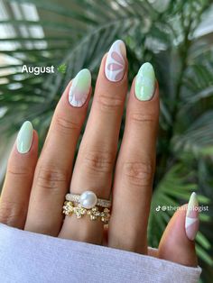 a woman's hand with green and white manicures on it, holding a ring