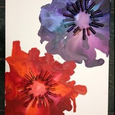 three different colored flowers are on a white paper with black trimmings and one is purple, the other has orange