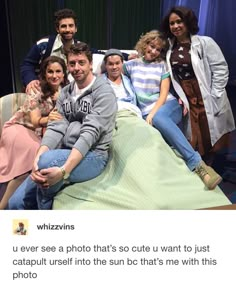 a group of people sitting on top of a bed in front of a blue curtain