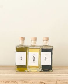 three bottles of oil sitting on top of a wooden table