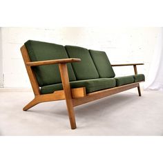 a green couch sitting on top of a white floor next to a wooden frame chair