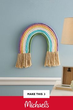 a rainbow wall hanging on the side of a blue wall next to a white lamp