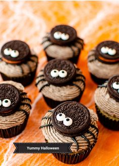 chocolate cupcakes decorated with oreo cookies and spider eyes on an orange surface