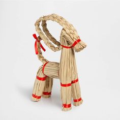 a dog made out of straw with red ribbon around it's neck and tail