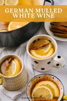 two mugs of german mulled white wine with orange slices and cinnamon on the side