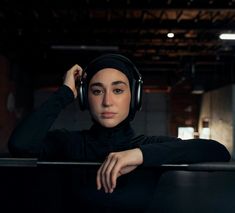 a woman wearing headphones leaning on a rail