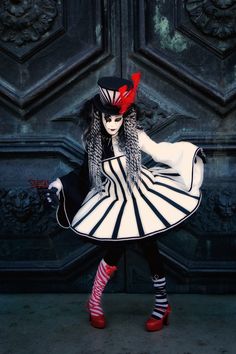 a woman dressed in black, white and red is posing for the camera with her hands on her hips