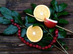 oranges, cranberries and apples are arranged on a wooden table with leaves