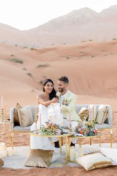 a newly married couple sitting on a couch in the desert