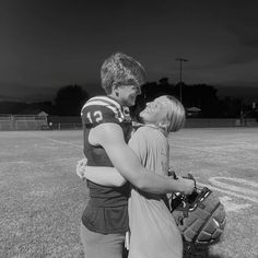 a man and woman embracing each other on a football field with the sky in the background