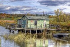 an old house sitting on top of a wooden dock next to a body of water