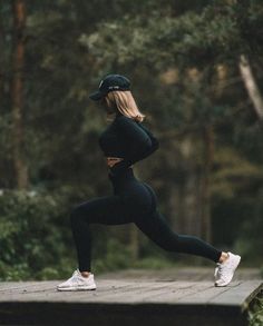 a woman in black sports bra and leggings is running on a wooden platform