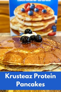 a stack of pancakes with blueberries and syrup on top, next to a box of krusteaz protein pancakes