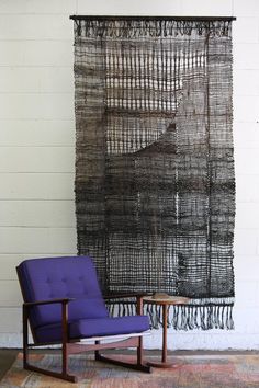 a purple chair sitting in front of a woven wall hanging