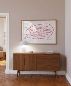 an empty room with a wooden sideboard and a poster on the wall above it