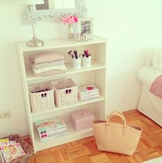 a white book shelf sitting on top of a hard wood floor next to a bed