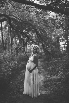 a pregnant woman is standing in the woods