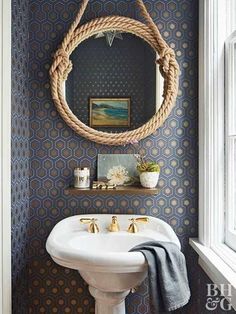 a white sink sitting under a mirror in a bathroom next to a rope hanging on the wall