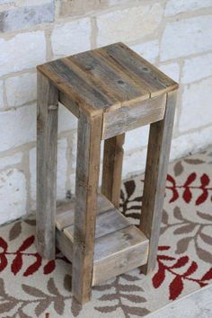 a small wooden stool sitting on top of a rug next to a brick wall and floor