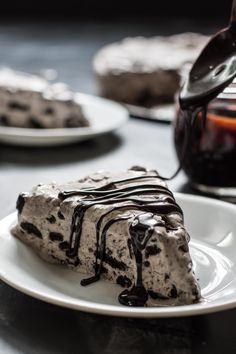 a slice of ice cream cake on a white plate with chocolate sauce drizzled over it