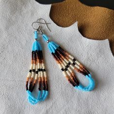 These teardrop beaded earrings are made with stainless steel findings, and three hanging loop strands of Japanese Miyuki and/or Czech beads. Most earrings I make in this style have a pattern in groups of fours or sevens. Four being for the four directions, and seven being for the seven clans of my tribe.  The palette used to make these earrings remind me of Native American Southwestern clay pottery. Colors used in this design: cream, black, dark brown, brown, cedar, and turquoise blue. From top of hook to bottom bead is approximately 3.5" long.  Hooks are stainless steel and come with clear backings.  Nickel free product. Made in a pet free, smoke free, and peanut free home. 100% Native American made with love. My earrings are made for all wearers. ♡ Beading Patterns Free Native American, Sarape Pattern, Pottery Colors, Native American Beadwork Earrings, Indigenous Crafts, Native Fashion, Native Beading, Seed Bead Jewelry Patterns, Native Beading Patterns