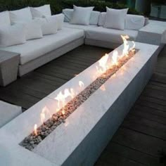 an outdoor fire pit with lots of rocks and stones on it's sides, surrounded by white couches