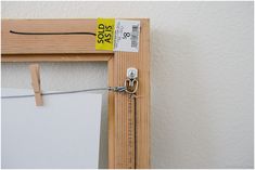 a wooden frame with a measuring tape on it and a pair of scissors hanging from the side