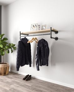 a coat rack with two coats hanging on it next to a potted plant and shoes