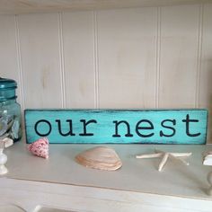 a sign that says our nest next to shells and seashells on a table