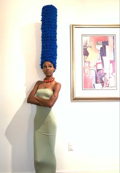 a woman with blue hair is standing in front of a painting and posing for the camera