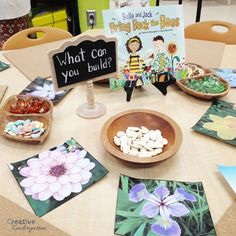 a table topped with lots of cards and plates filled with flowers next to a sign that says what can you build?