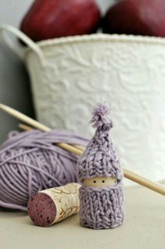 two balls of yarn and some knitting needles on a table with apples in the background