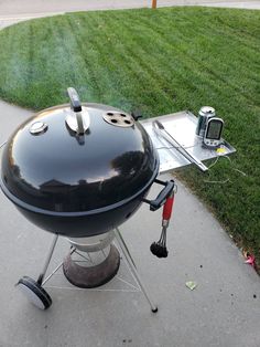 an outdoor bbq grill on the side of a sidewalk next to a green lawn