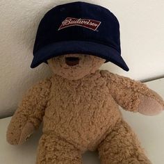 a brown teddy bear with a blue hat on it's head sitting against a wall