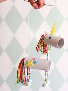 a person holding a toothbrush next to a paper roll unicorn mobile