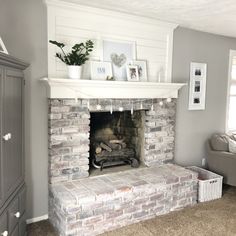 a living room with a fire place and pictures on the fireplace mantel above it