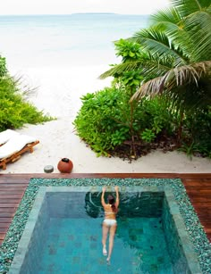 a man is swimming in a pool surrounded by greenery