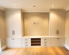 an empty room with white cabinets and wood floors