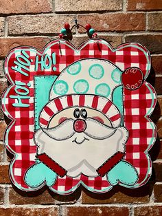 a red and white sign with a santa clause on it's face in front of a brick wall